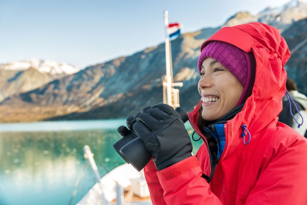 Alaska cruise travel woman looking at wildlife with binoculars