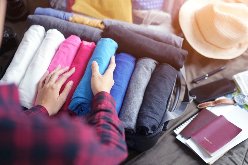 Woman packs clothes in suitcase bag