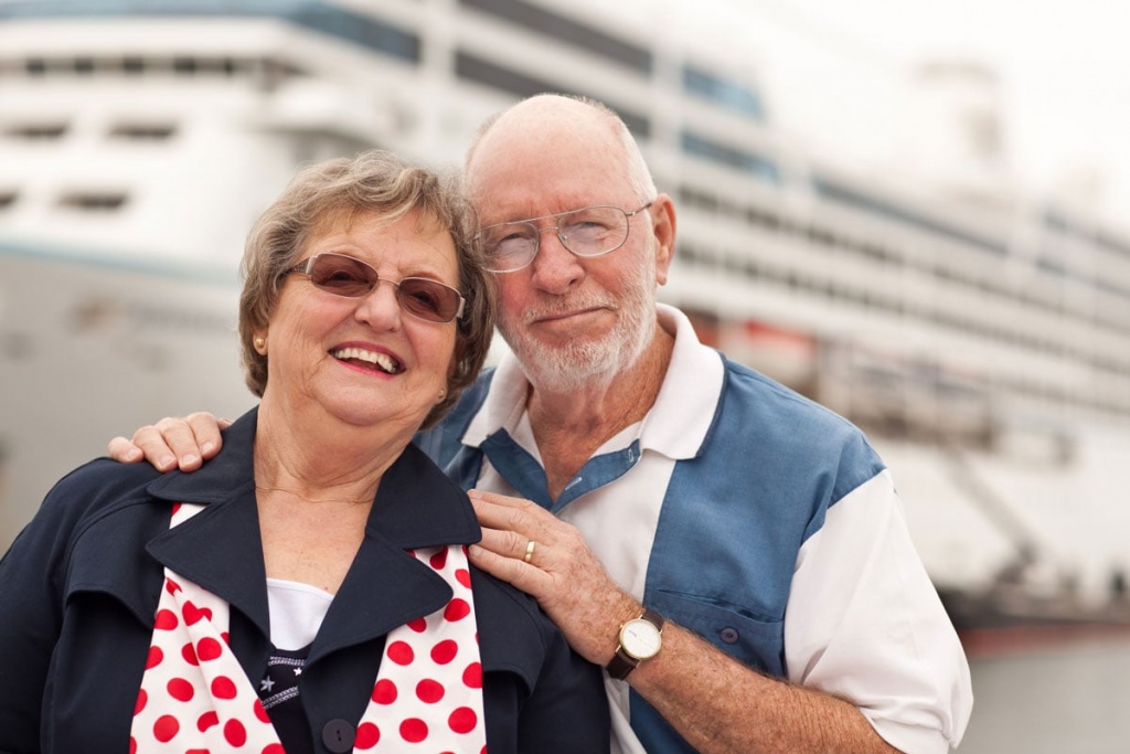 senior couple on shore in front of cruise ship