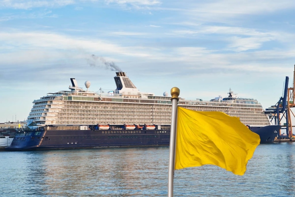 Cruise ship on a port deck. Quarantine yellow flag warning of Coronavirus infectious disease