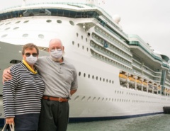 Senior Couple Wearing Face Masks Standing In Front of Cruise Ship