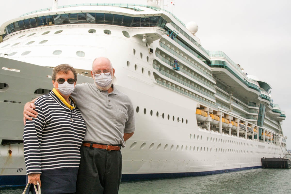 Senior Couple Wearing Face Masks Standing In Front of Cruise Ship